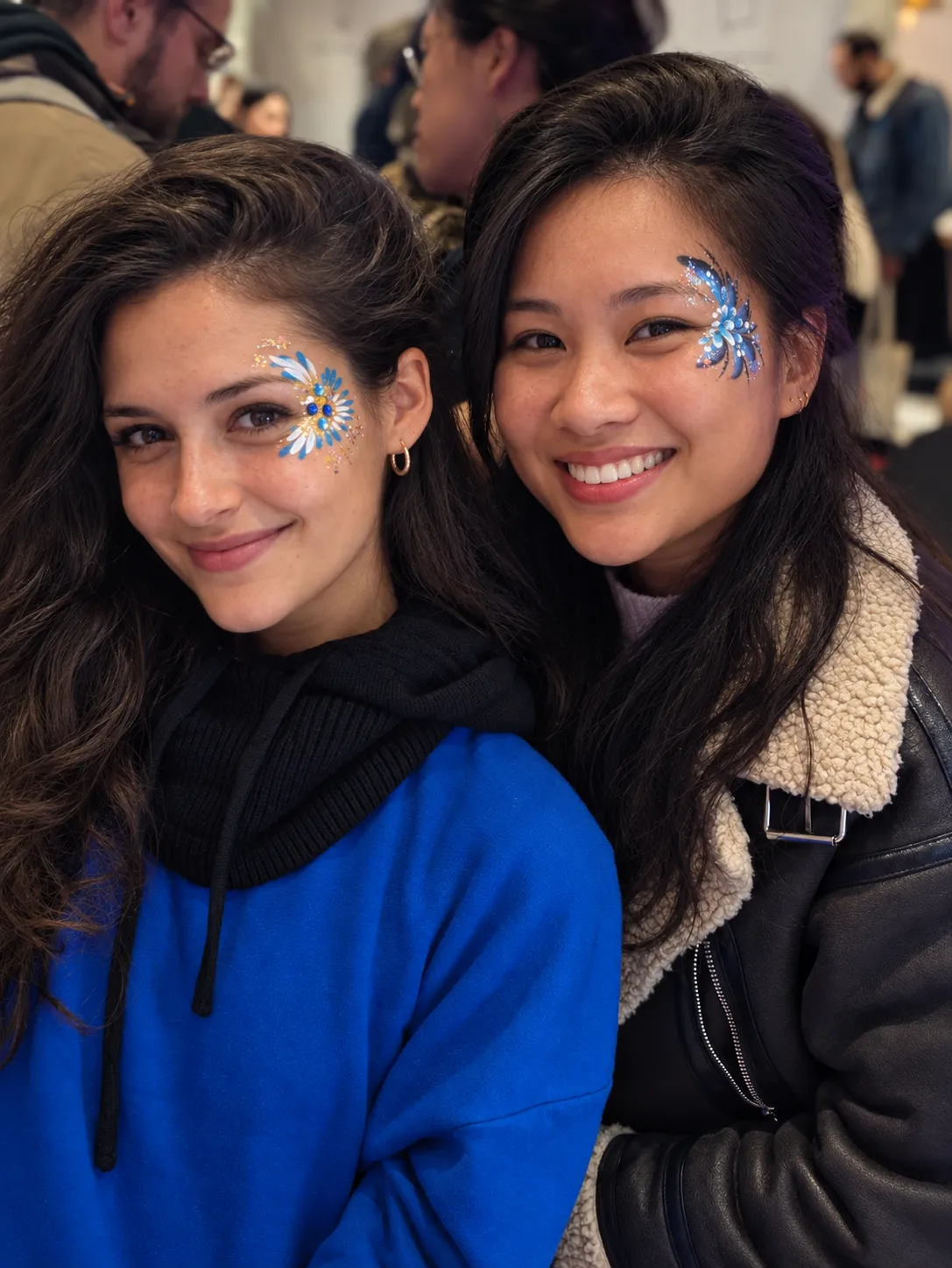 Deux invitées souriantes, maquillées de strass et de paillettes